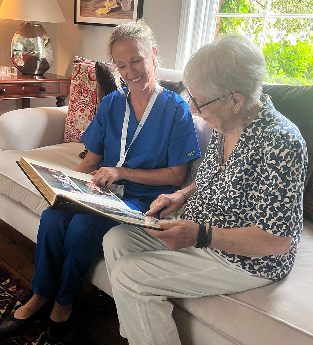 CM Bespoke carer looking at photo album with elderly woman