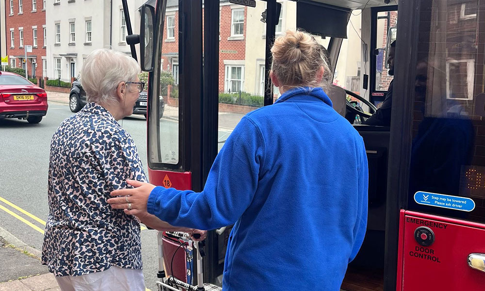 A woman receiving support as she boards a bus