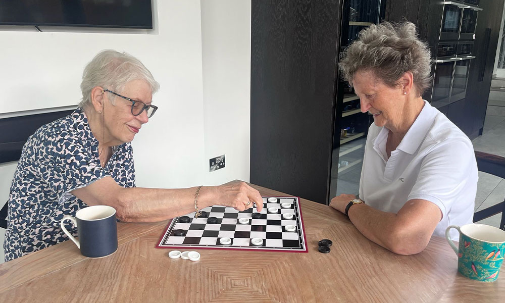Two women playing draughts together at a table